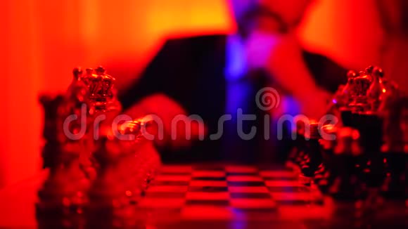 一个穿着商务服的人坐在模糊的背景上下棋在明亮的红光中射击视频的预览图