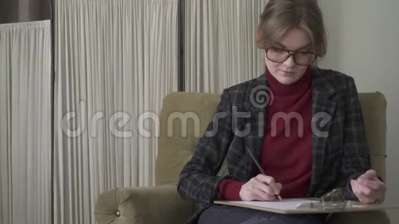 戴眼镜的严肃的年轻女人在剪贴板上写字视频的预览图
