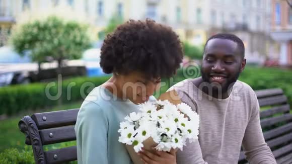 美丽的非洲女孩在约会时喜欢鲜花甜蜜的一对拥抱视频的预览图