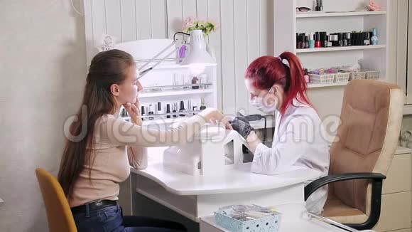 在美容院带手套的女性美甲师在涂胶前先给顾客做一五金美甲视频的预览图
