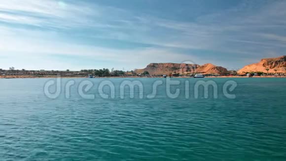 夏季山水蓝蓝绿松石海映衬着沙漠山脉的黄色海岸棕榈树海滩和旅馆视频的预览图