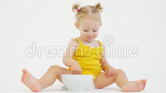 小女孩用勺子在白色背景下吃早餐视频的预览图