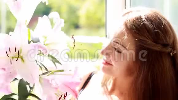 美丽的女人看着百合嗅着花香视频的预览图