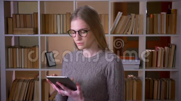 用平板电脑为年轻漂亮的女学生戴上眼镜并在镜头中显示绿色屏幕视频的预览图