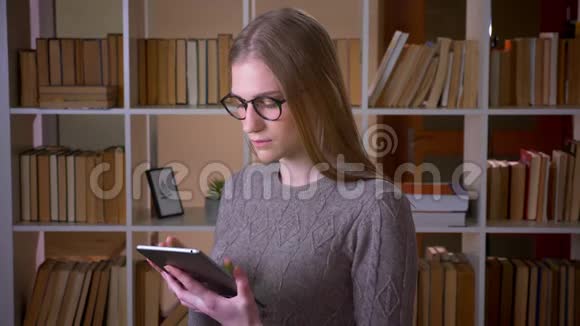用平板电脑为年轻有魅力的女学生戴上眼镜并显示绿色彩色屏幕视频的预览图