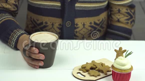 男人手把姜饼放在可可里在桌子上小蛋糕视频的预览图