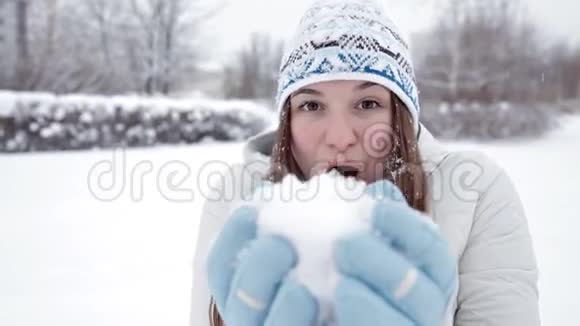 一个年轻的女孩在冬天的天气里高兴在公园里打雪球视频的预览图