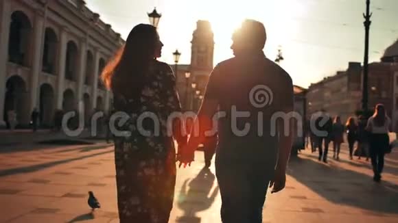 户外生活方式照片年轻情侣在夕阳后的街道上漫步视频的预览图