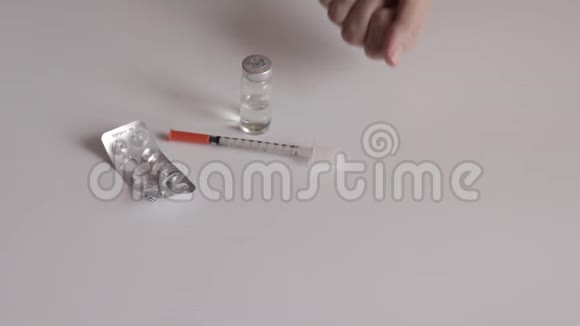 一个女人手里拿着白色药片把它扔了下来白色桌子背景上的空水泡西林热和小瓶视频的预览图