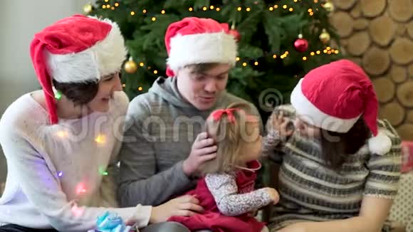 朋友们和小女孩一起玩礼物有火花和圣诞树的背景圣诞节假期圣诞家庭视频的预览图