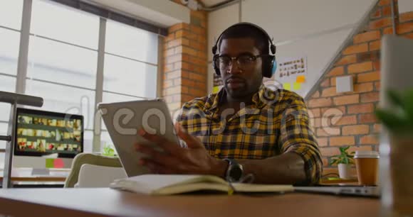 男性平面设计师在办公桌旁听音乐视频的预览图