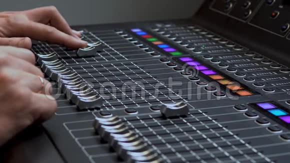 人在专业的电子音响调音台上工作调节声音通道的控制面板视频的预览图
