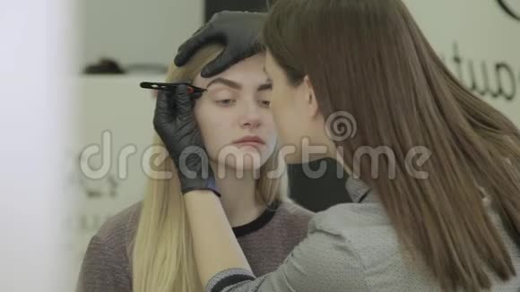 化妆师在美容院给一个年轻女孩挑眉毛视频的预览图