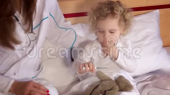 患病儿童在床上发烧并在医生监督下测量体温视频的预览图