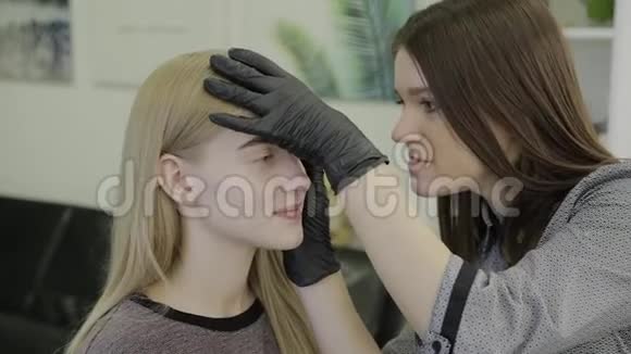 化妆师在美容院给一个年轻女孩挑眉毛视频的预览图