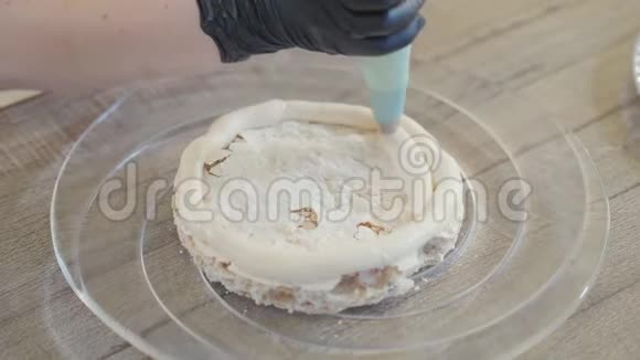 将一层甜蛋糕贴在玻璃板上用黑色乳胶手套将奶油涂在上面视频的预览图