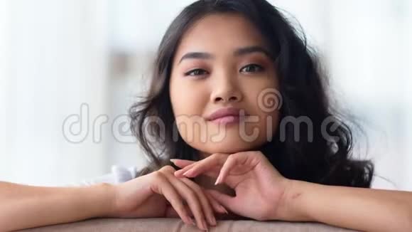 可爱的年轻亚洲模特在浅白色背景下微笑摆姿势的特写肖像视频的预览图