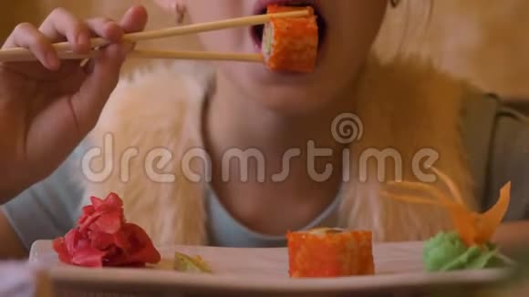 年轻的少女在日本咖啡馆里用筷子吃寿司卷视频的预览图