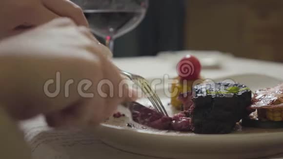 年轻女人用叉子和刀子把美味的鲜肉放在盘子里切视频的预览图