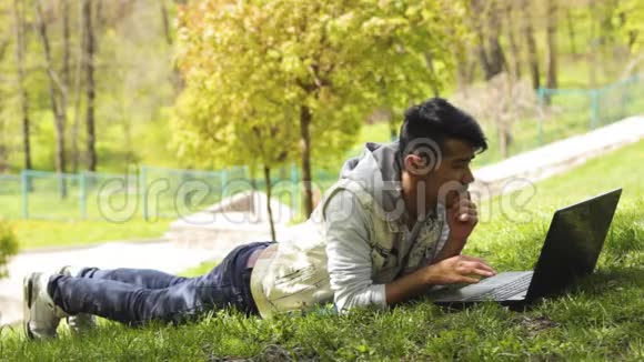 一个在笔记本电脑上工作躺在草地上的自由职业者视频的预览图