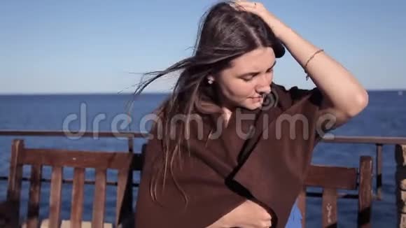 一个女孩坐在海边的咖啡馆里裹着一条被风吹过的毯子头发风海视频的预览图
