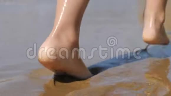 孩子沿着海浪走幼儿波浪背景上的脚海水冲走了脚印视频的预览图