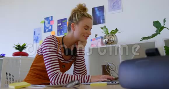 白人女性在办公室里用笔记本电脑工作的侧视视频的预览图
