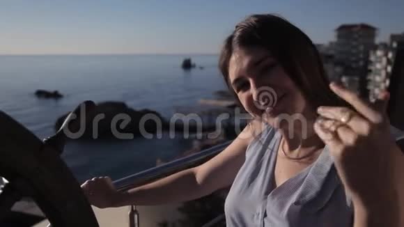 清晨一个年轻的女孩站在酒店房间的露台上俯瞰大海并呼唤她的丈夫视频的预览图