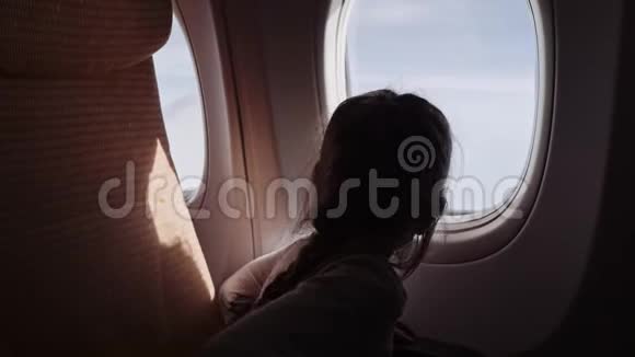 可爱的女孩带着棒棒糖看着飞机上的窗户视频的预览图