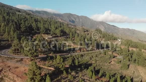 空中射击汽车在日落时行驶在一条山路上发夹转动飞回去周围是绿色森林视频的预览图