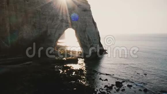 无人机沿着诺曼底海岸史诗般的白色悬崖飞向天然背光的岩石拱门和快乐的旅游情侣视频的预览图