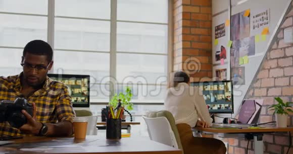 男性平面设计师在书桌4k处检视数码相机照片视频的预览图
