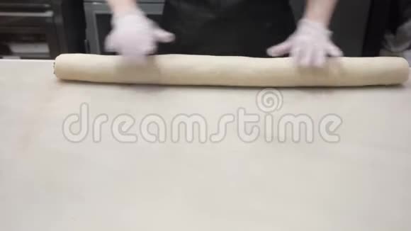 场景库克将包裹好的面团与肉桂馅料在一卷中对齐生产肉桂卷面包制品视频的预览图