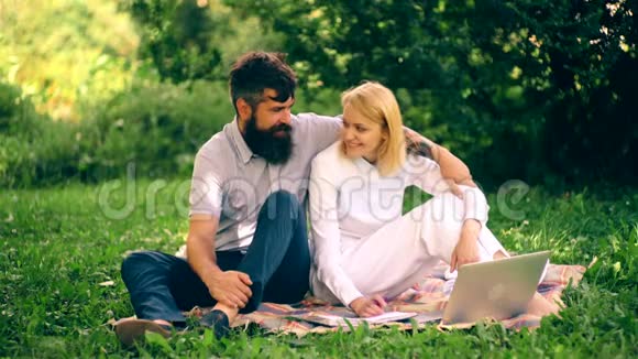 女孩和她的男朋友坐在公园的毯子上聊天一个男孩抱着一个女孩坐在毯子上视频的预览图