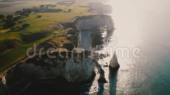 在著名的白垩海边悬崖和拱门之上在诺曼底的埃特雷塔田园绿色的日落田野上飞翔视频的预览图