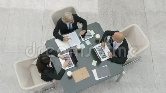 三个公司商务人员在办公室用笔记本电脑开会视频的预览图