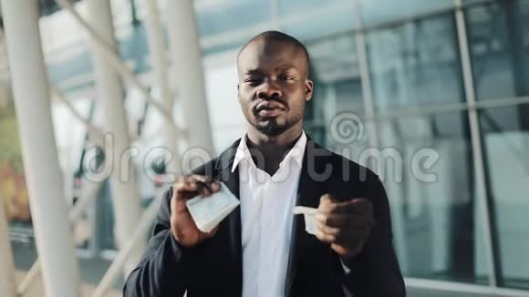 非裔美国商人撕美元钞票他站在办公楼附近货币贬值股票市场视频的预览图