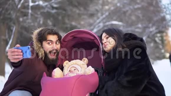 夫妇与婴儿自拍散步年轻的已婚夫妇带着婴儿车在冬天散步自拍现代青年视频的预览图