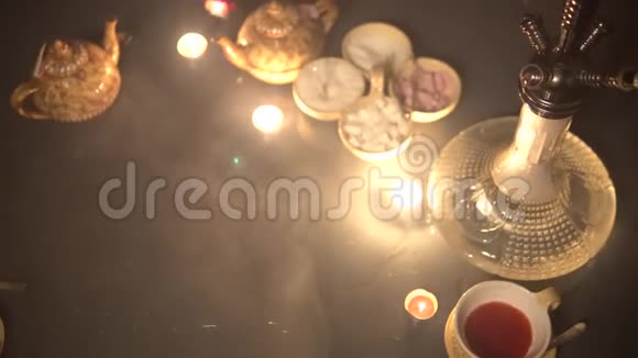 玻璃桌面上的胡卡杯烛和智能手机东方茶道时尚的东方石沙在黑暗与背光SS视频的预览图