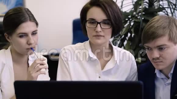 女商人正在帮助项目工作人员在办公室导师解释如何使用笔记本电脑软件创建项目视频的预览图