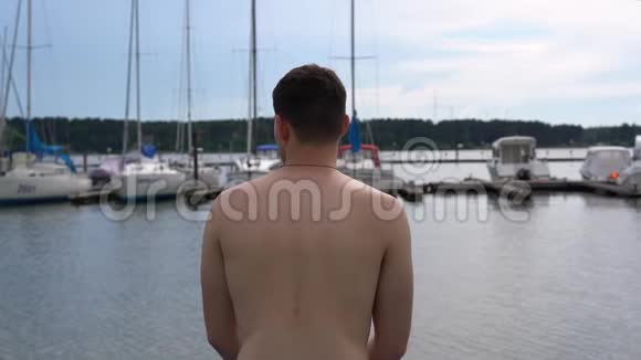 一个年轻人坐在码头上看着游艇视频的预览图