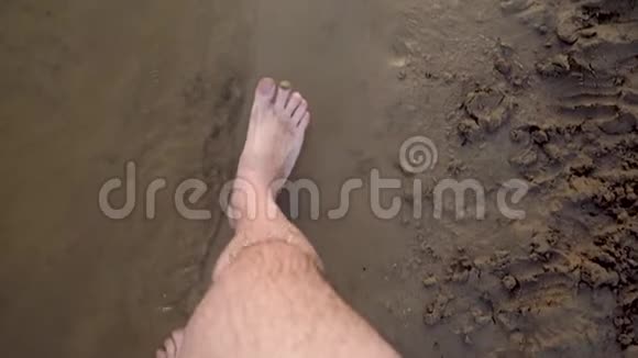 男人脚沿着海滩沿着水边走慢动作特写视频的预览图