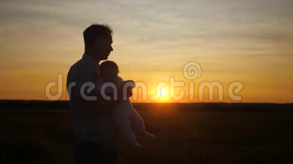 日落时婴儿在他父亲的手中慢动作视频的预览图