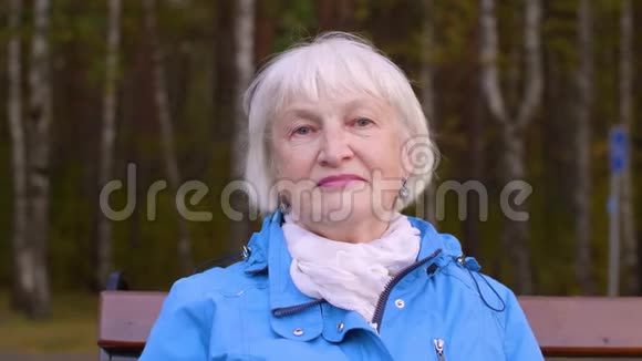 秋天公园的长椅上有一位白发苍苍的老妇人在看镜头视频的预览图