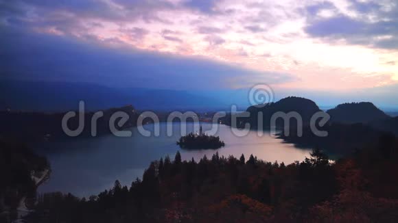 以阿尔卑斯山山脉为背景的斯洛文尼亚小岛布莱德湖和教堂的空中日落景色视频的预览图