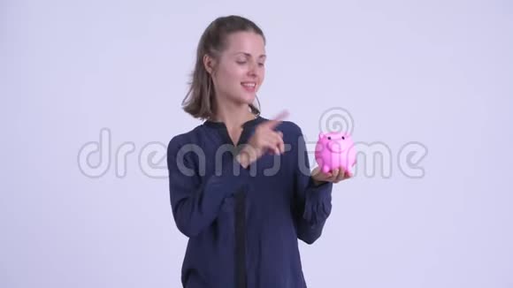 快乐的年轻漂亮的女商人拿着储蓄罐竖起大拇指视频的预览图
