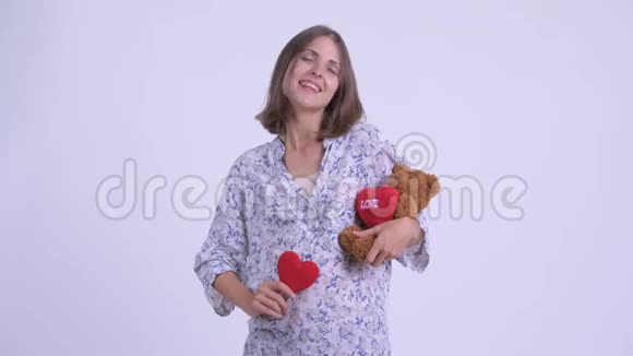 幸福的年轻孕妇抱着心玩具熊视频的预览图