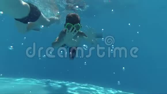 快乐男孩潜入游泳池看镜头水下拍摄阳光照射视频的预览图