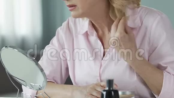 不满意的女人50多岁看着一面手镜反龄化妆品视频的预览图