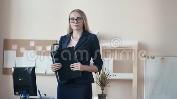 呼叫中心员工在办公室工作一个戴着眼镜的金发女孩站在办公室手里拿着一个视频的预览图